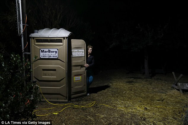 Marva Ericson, 48, exits a porta potty in a parking lot in the middle of the night in Santa Barbara. She is part of a safe parking program for people living in their vehicles