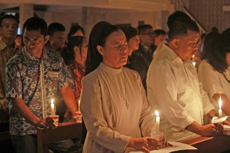 Umat Kristiani menyalakan lilin pada Misa Natal di gereja Santo Kristoforus Kota Gorontalo, Gorontalo, Minggu (24/12/2017). Perayaan Natal yang diikuti ratusan umat Kristiani tersebut mengambil tema Hendaklah Damai Sejahtera Kristus Memerintah Dalam Ha timu.