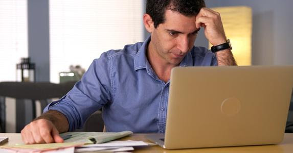 Frustrated man working on finances with a laptop © Rocketclips, Inc./Shutterstock.com