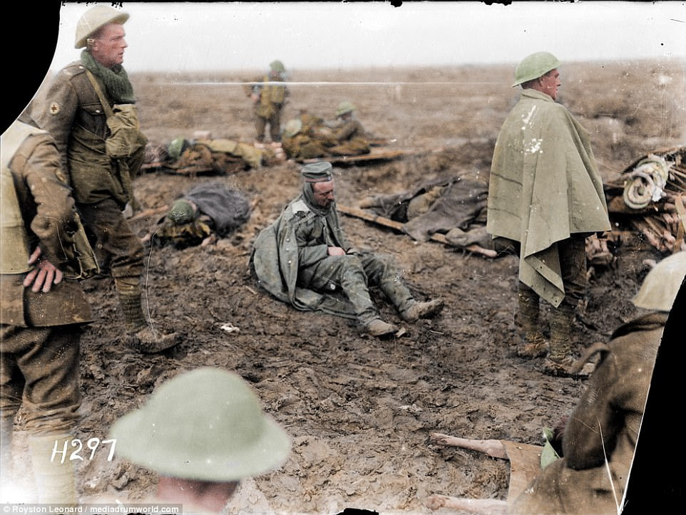 This photo shows French soldiers at the Battle of Verdun. One sits on the mud as others help the wounded