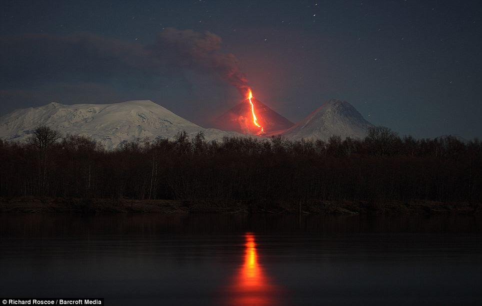 The eruption of the Kliuchevskoi volcano is shown reflected in the Kamchatka river. 