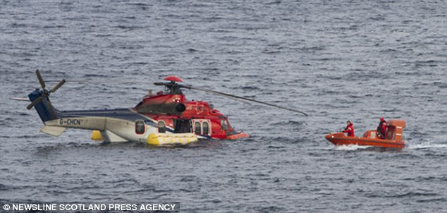 Emergency: Rescuers head towards a Super Puma helicopter which was forced to make an emergency landing off the coast of Shetland with 19 oil rig workers on board