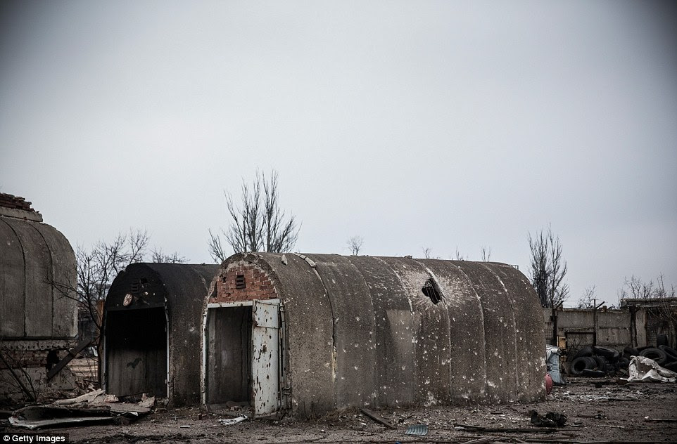 A flimsy building remains standing but covered in shelling damage and bullet holes amid the rubble of Donetsk