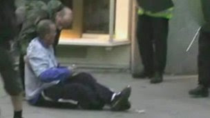 Ian Tomlinson sitting on the pavement after being pushed over