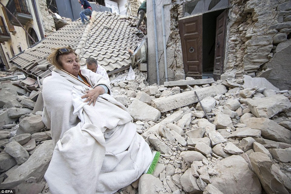Encolhido: Uma mulher chocado e homem são vistos envolto em cobertores na frente de casas destruídas em Amatrice, Itália central