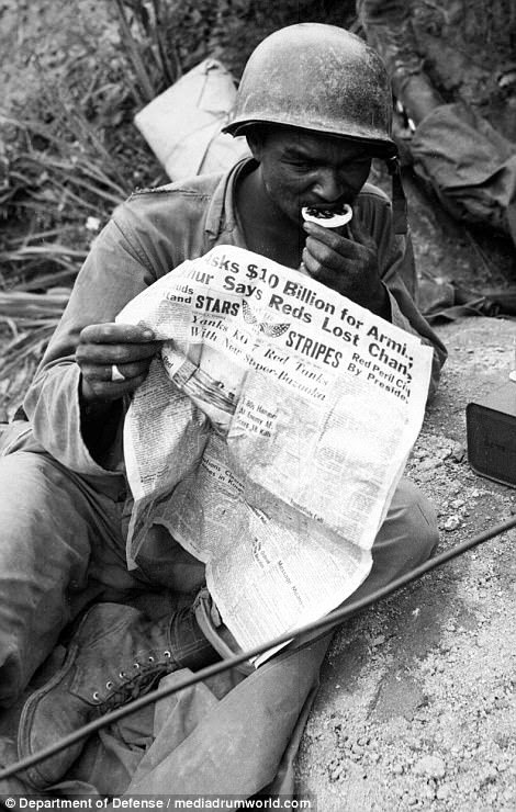 Pfc Clarence Whitmore, voice radio operator, 24th Infantry Regiment, reads the latest news during lull in battle, near Sangju, Korea, on August 9, 1950