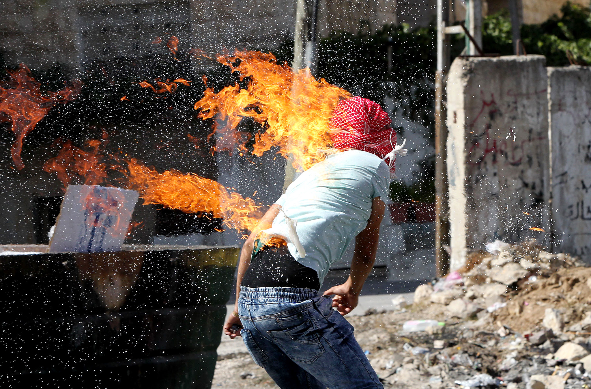 The clothes of a Palestinian student from Hebron University burn after he set himself on fire while throwing a Molotov cocktail towards Israeli soldiers and border police during clashes after the protesters blocked the main north entrance of the West Bank town of Hebron with stones and tyres on October 13, 2015. The rising tide of unrest, which has seen a series of stabbing attacks and violent protests, has raised fears that a full-scale third Palestinian uprising, or intifada, could erupt. AFP PHOTO / HAZEM BADERHAZEM BADER/AFP/Getty Images