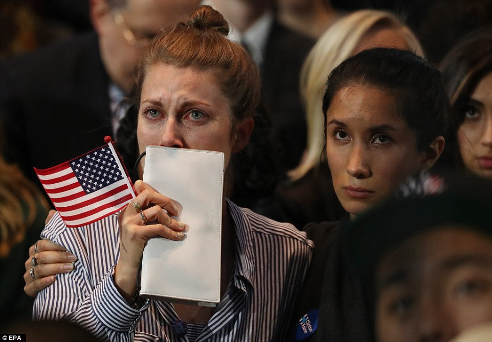 As pessoas na multidão em 2016 evento US presidencial da noite da eleição de Hillary Clinton assistir em lágrimas como resultados vêm em uma grande tela no Centro de Convenções Javits