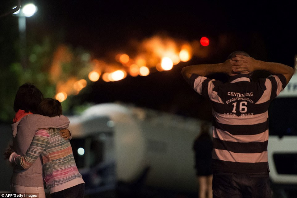 Um homem prende a cabeça entre as mãos e uma mulher abraça sua filha como eles olhar para os fogos na noite passada