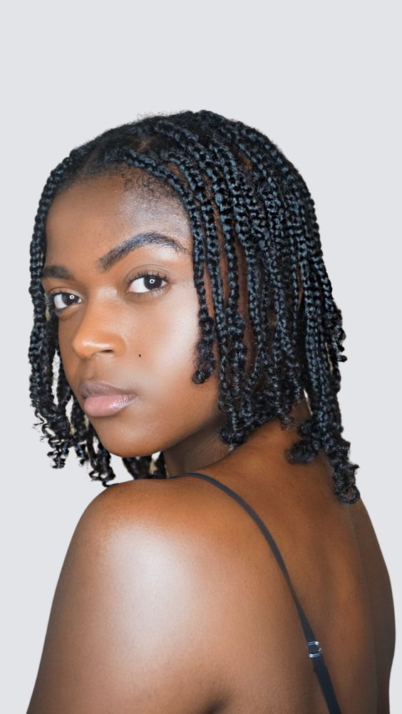 A woman in a natural box braid styling her natural short hair