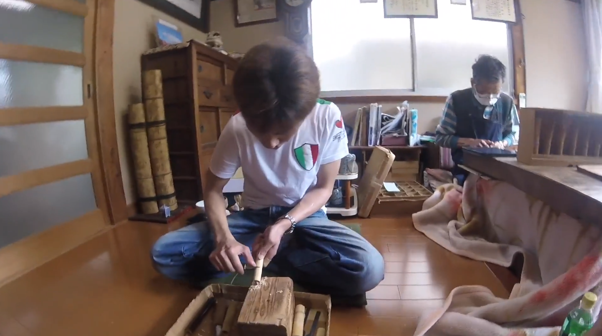un artisan japonais en train de fabriquer un fouet en bambou