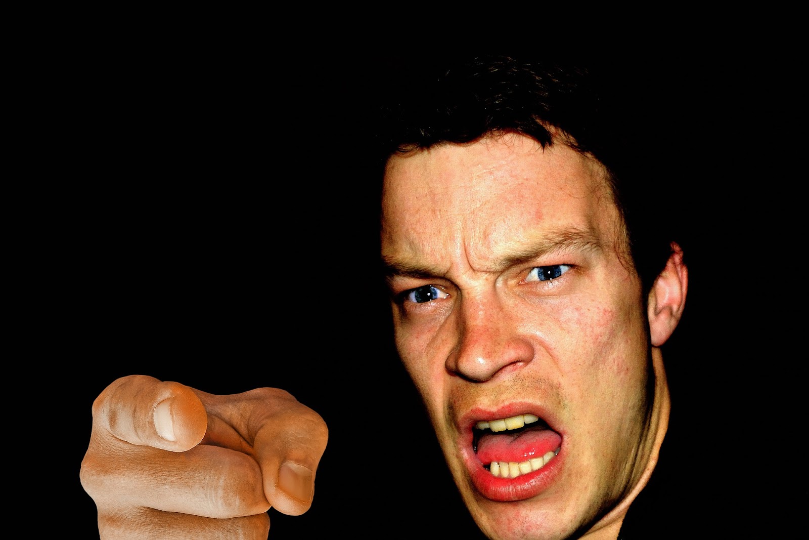 A picture of an angry man, screaming while pointing at the camera.