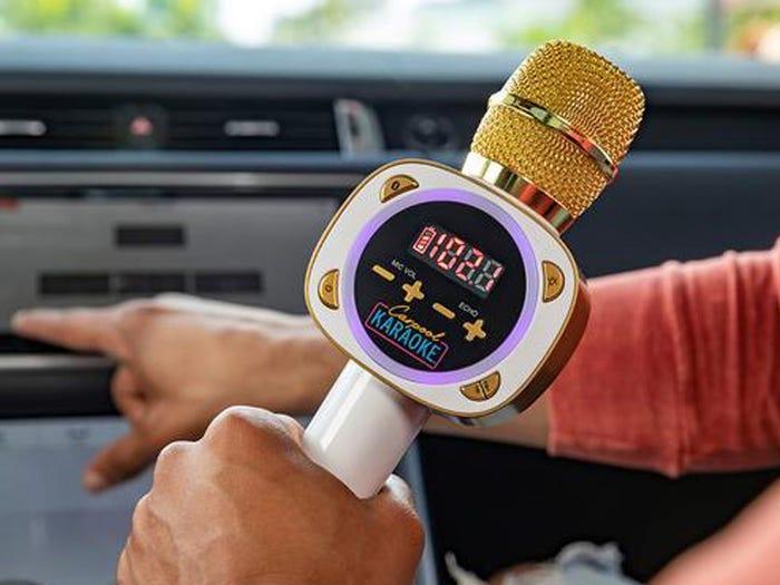 closeup of hand holding gold and white karaoke microphone - a great gift for tweens