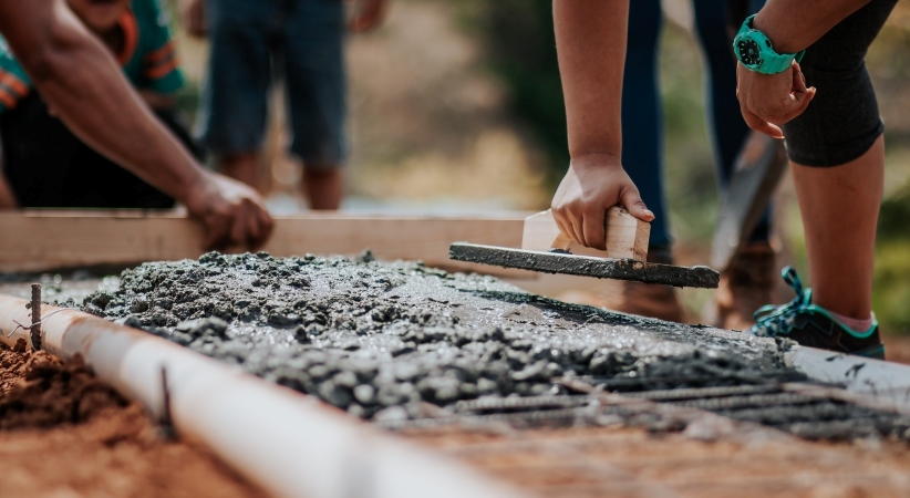 Several members of a community are working together to lay the foundation of a building during a volunteer event.