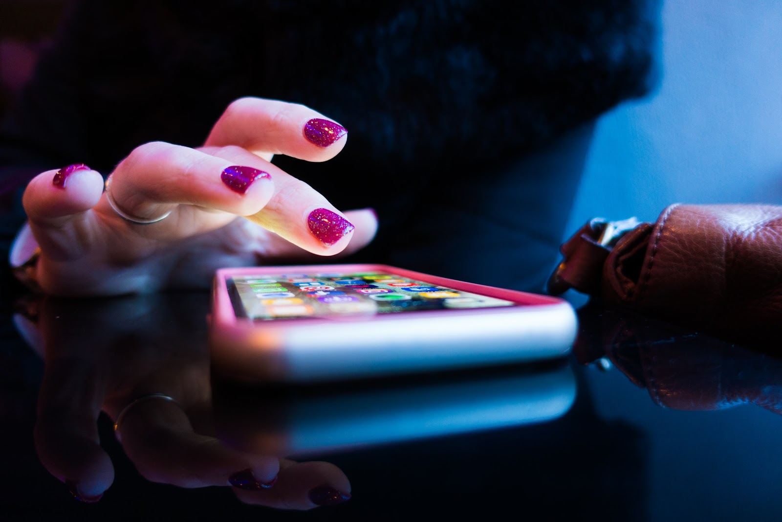 A hand with painted fingernails prepares to tap a touchscreen <mark><mark><mark><mark><mark><mark>cell phone</mark></mark></mark></mark></mark></mark>.