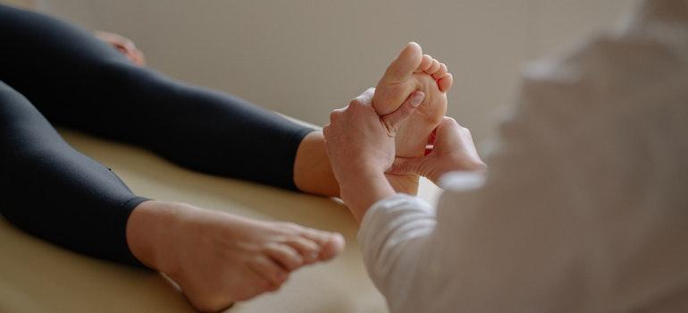 a therapist massaging pregnant woman's feet in a prenatal massage session