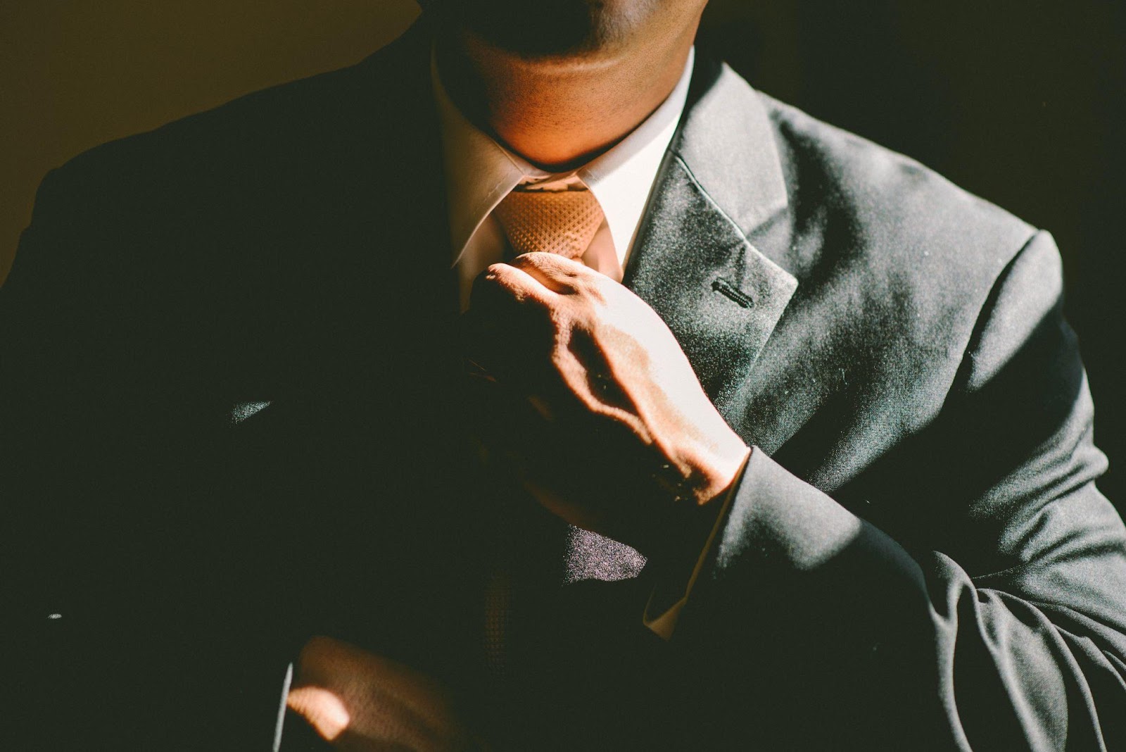 A businessman similar to Elijah Norton straightens his tie