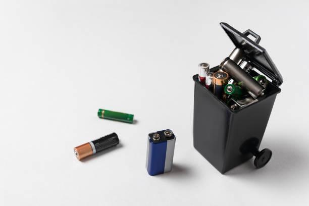Used batteries in the garbage container on white background. Electronic waste concept. Eco-friendly disposal.