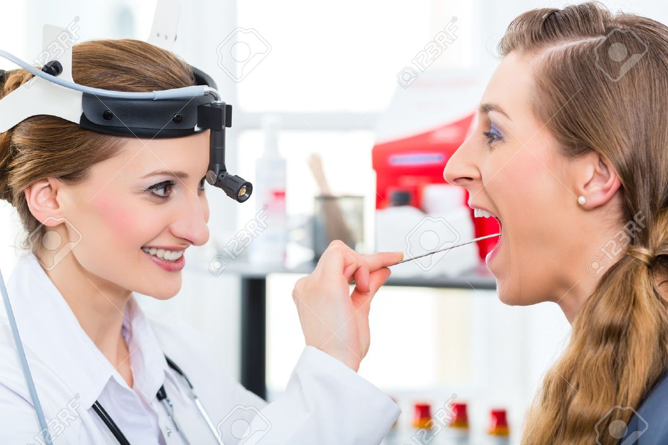 19806458-Doctor-Young-female-doctor-or-ENT-specialist-with-a-patient-in-her-practice-examining-the-throat-wit-Stock-Photo.jpg