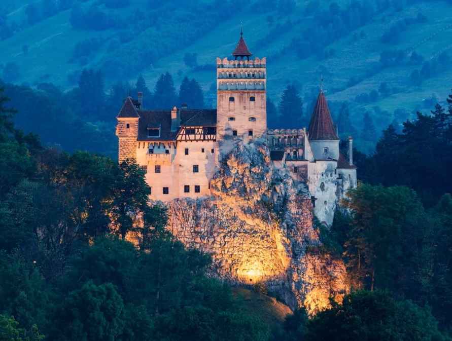 A castle on a rock with Bran Castle in the background

Description automatically generated