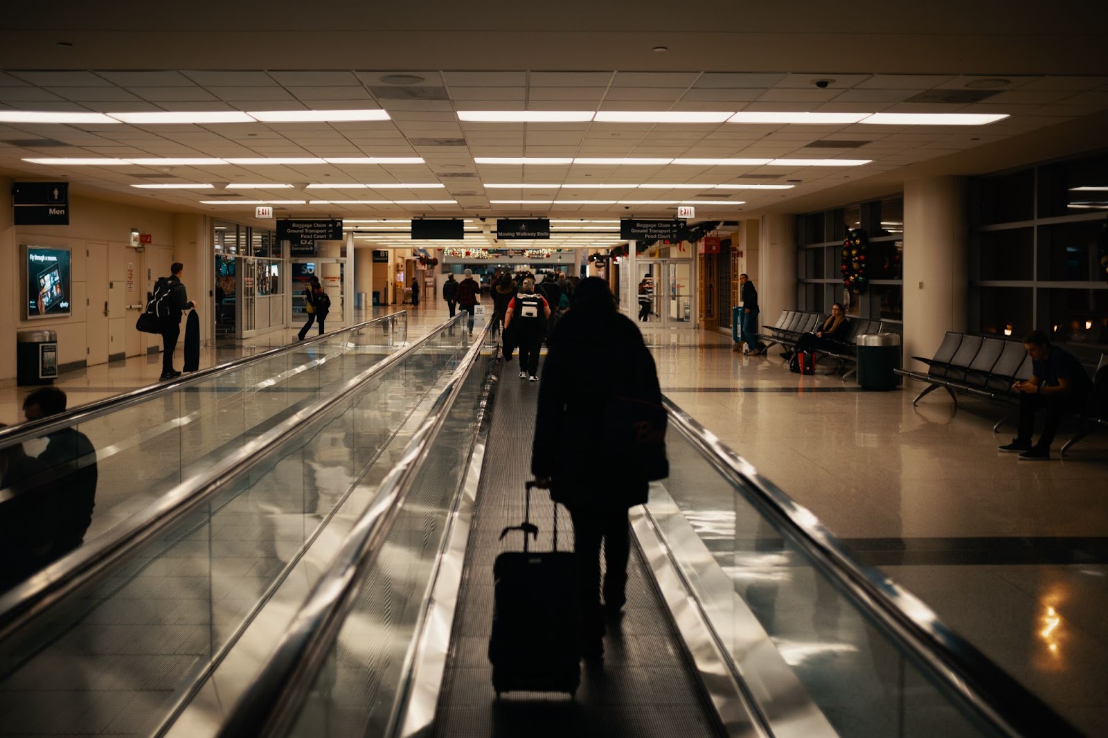 People walking through busy airport with suitcases