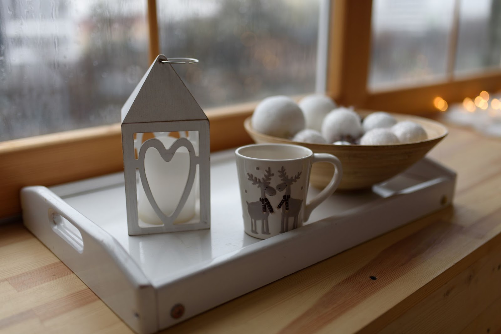 taca z kubkiem i świecznikiem stojąca na parapecie, w tle drewniane okno
