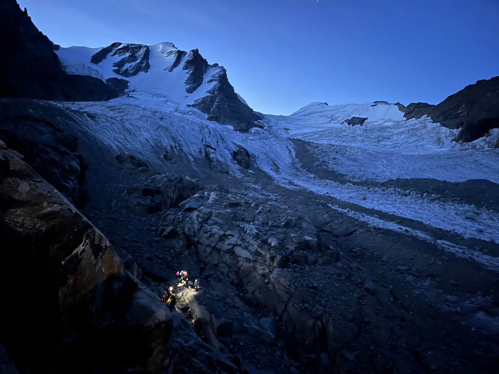 Climbers with head torches approaching the Gran Paradiso glacier as the sun begins to rise.