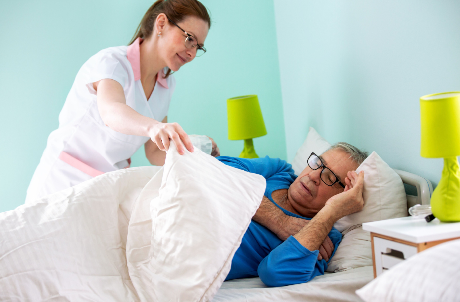 A female nurse helping a senior man to sleep.