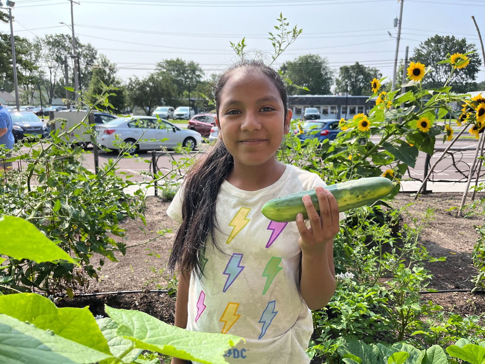 Little girl holding a cucumber in a garden