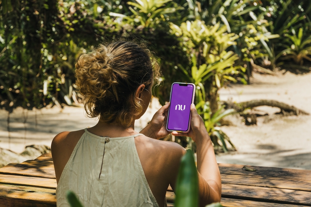 Woman with a smartphone on her hand, with Nubank's mobile app on the screen