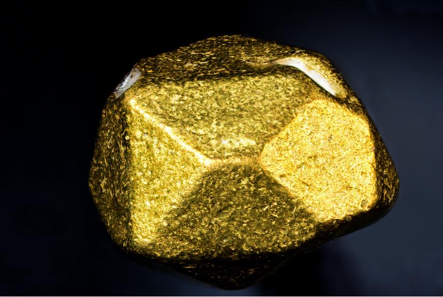 a macro-photography of piece of gold rock on a black background