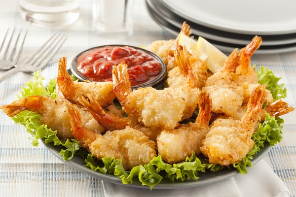 Shrimp covered in shredded coconut served with lettuce and ketchup
