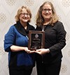 Two people posing for the camera while holding a plaque