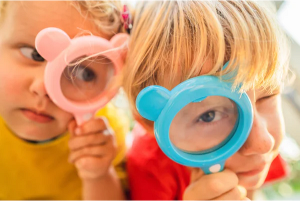 Two children with toy magnifying glasses on a scavenger hunt