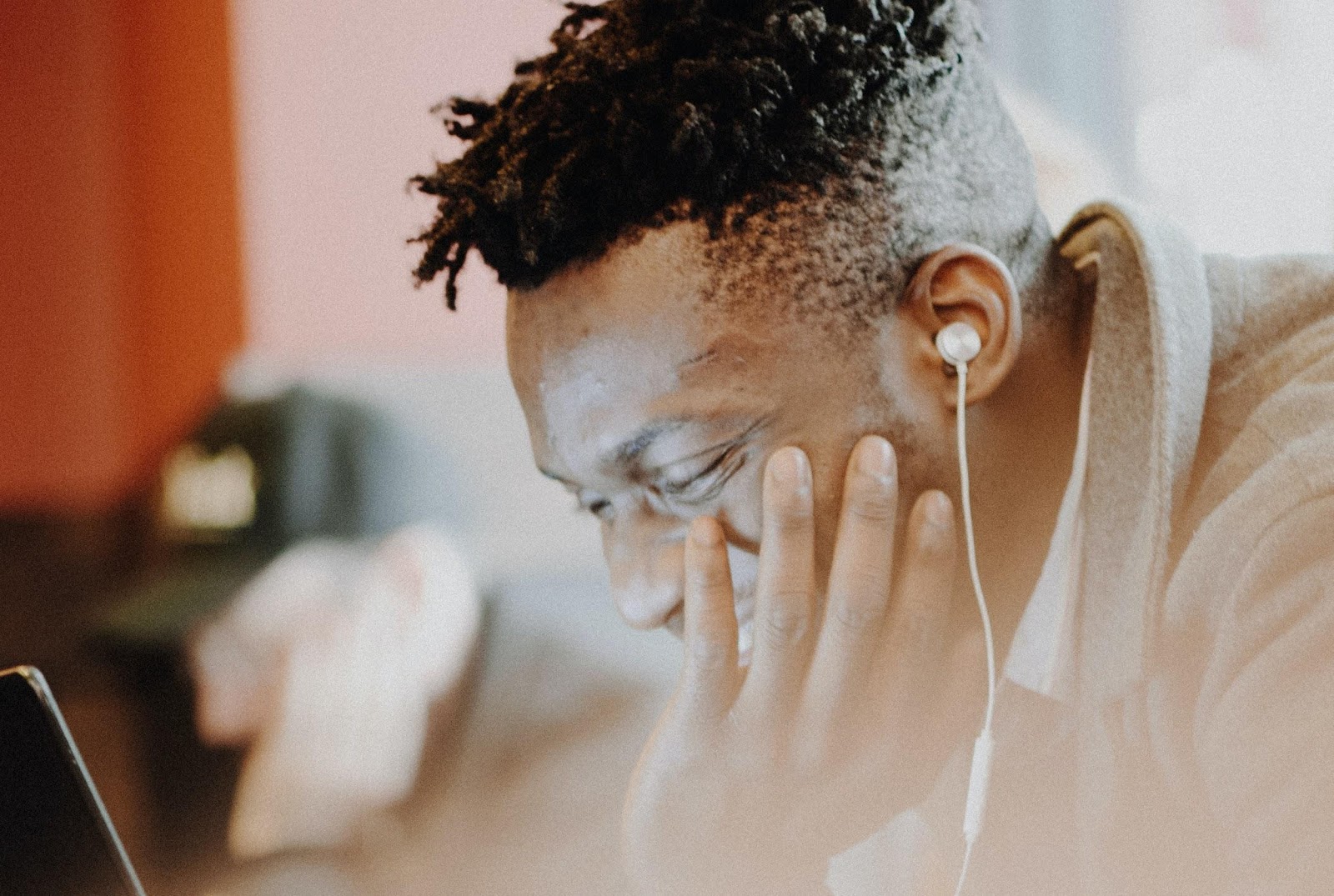 El hombre negro sonríe mirando una pantalla de su computador portátil con auriculares.
