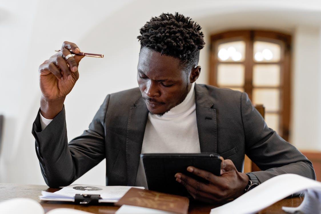Free Man in Black Suit Holding Black Tablet Computer Stock Photo