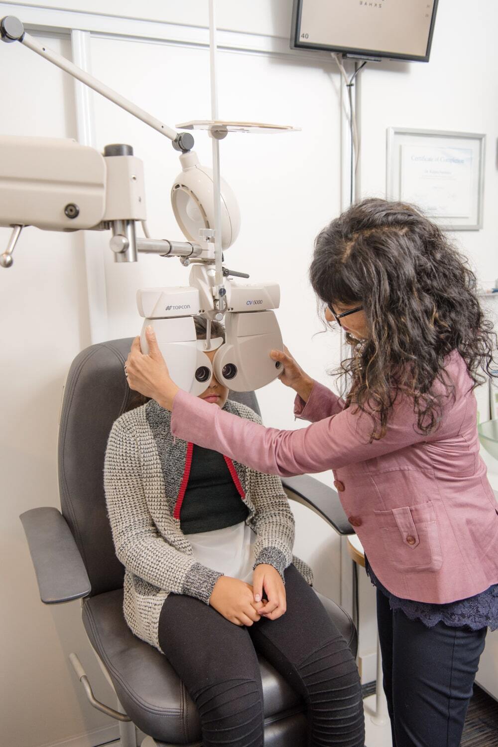 An eye doctor uses an electronic phoropter which places lenses in front of the patient's eyes.