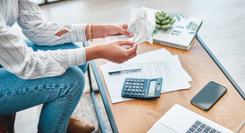 Office worker holding papers with laptop and calculator on desk