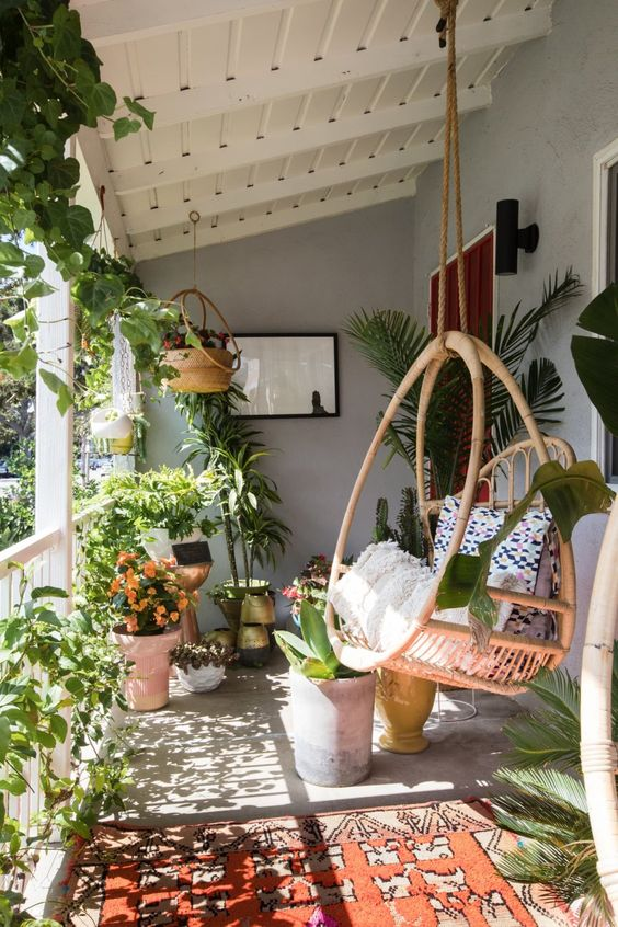 a balcony with a swing in it and full of plants