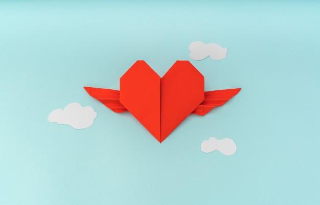 Red paper origami heart with wings and cloud on blue background Free Photo