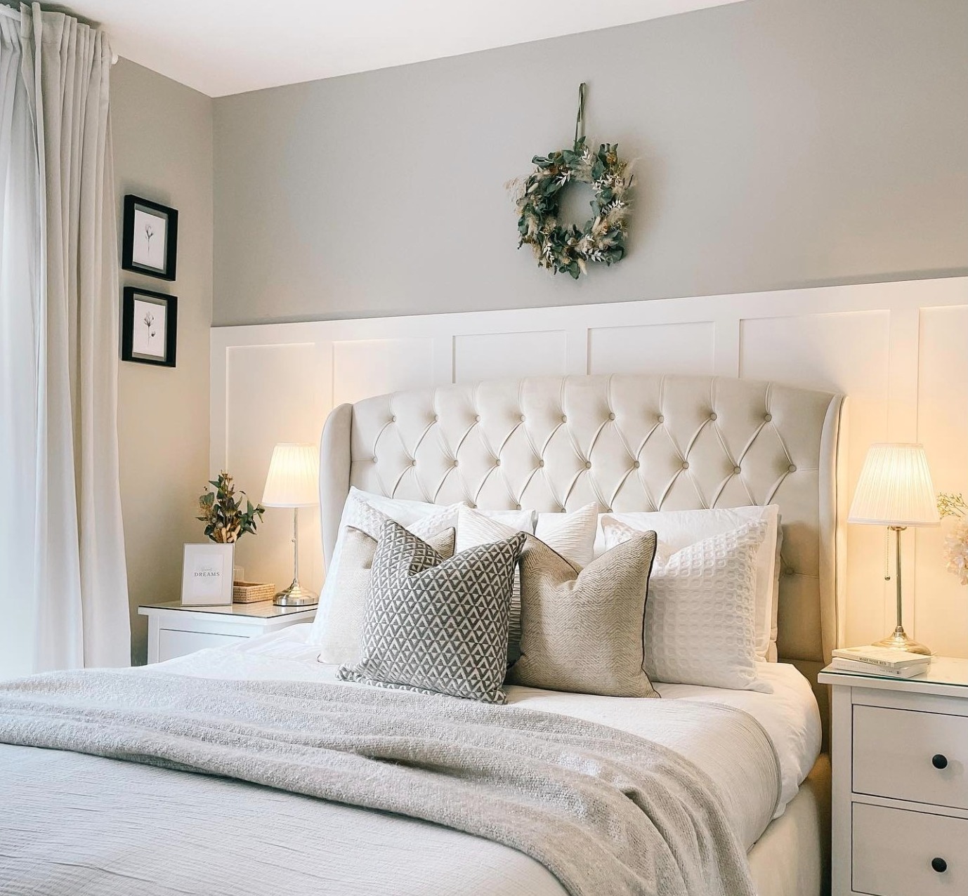 Bedroom painted in farrow and ball corn forth white, with pure white panelling. the bed has an upholstered headboard, and neutral curtains at the windows.