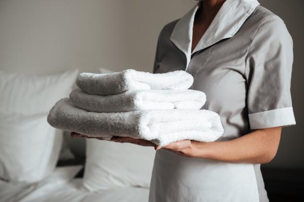 Young hotel maid standing and holding fresh clean towels Free Photo