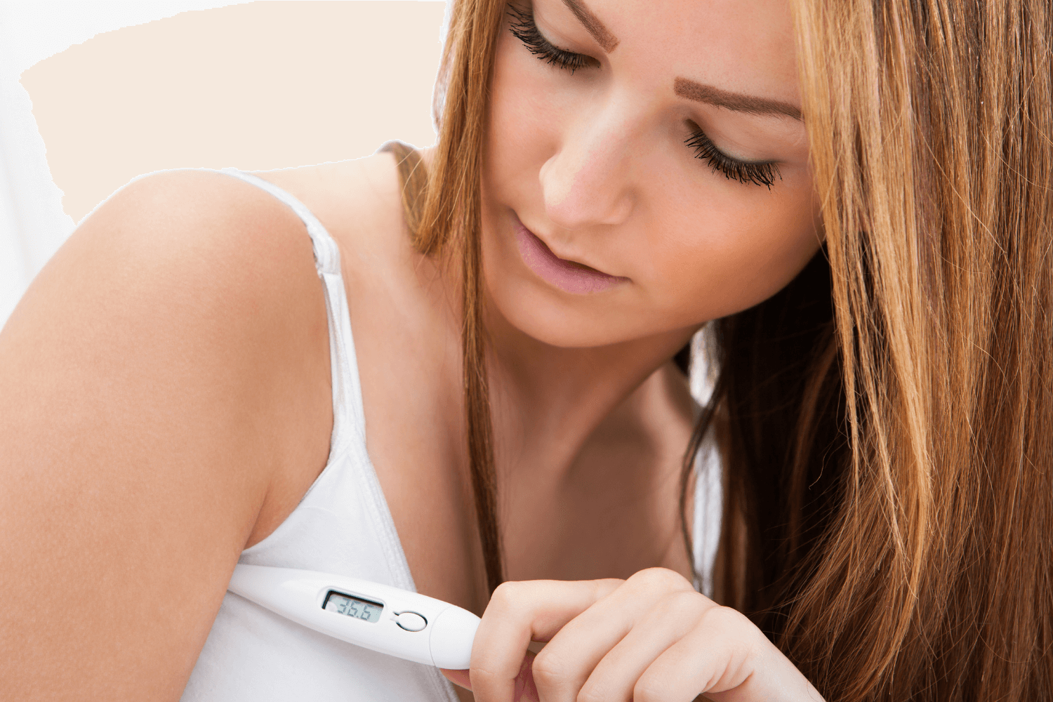 Woman taking her basal body temperature under her armpit using a thermometer