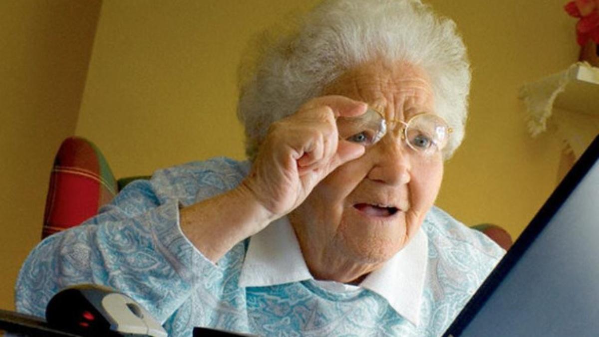 n image of a confused old woman staring at her laptop's screen.