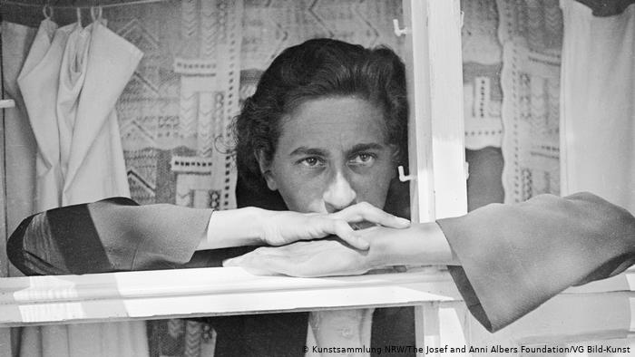 Anni Albers, a black and white photo of her shown looking out her window, one of our featured women in design.