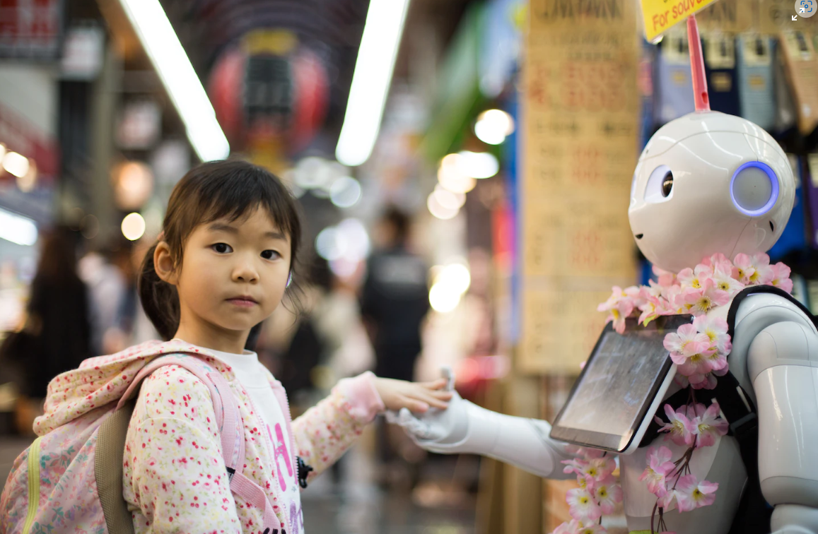 An Asian girl holds a robot's hand