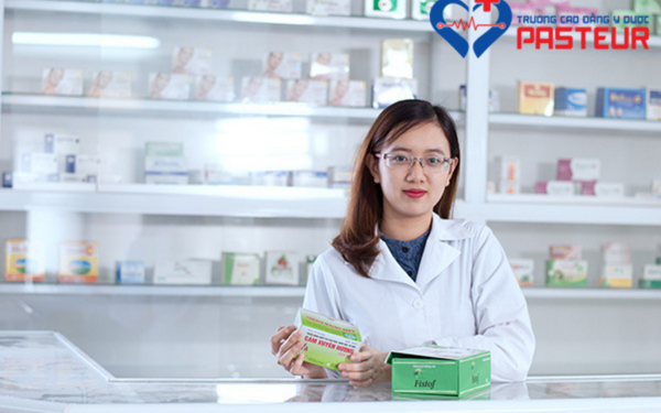 Dược sĩ tại nhà thuốc mặc áo blouse trắng, trên tay cầm hộp thuốc