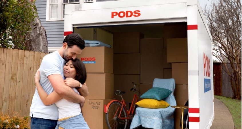 A couple hugging in front of their PODS portable moving container.