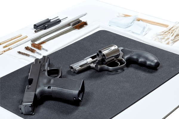 revolver and handgun lying on a pad with tools in preparation for cleaning