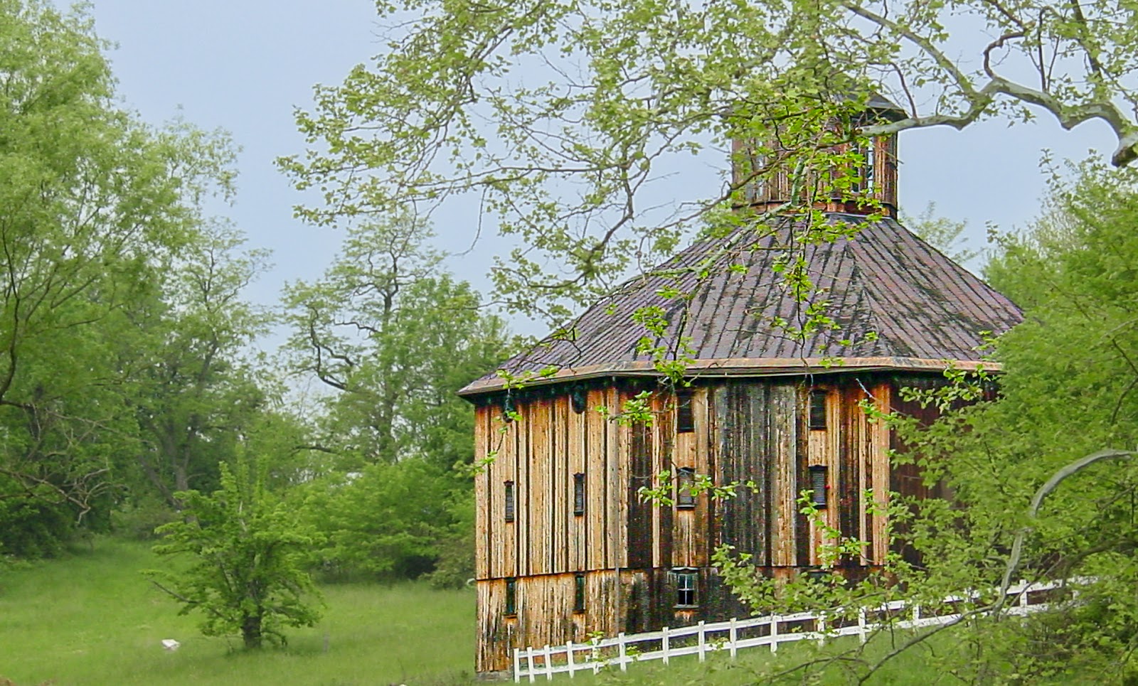 A weathered round wooden barn with small windows